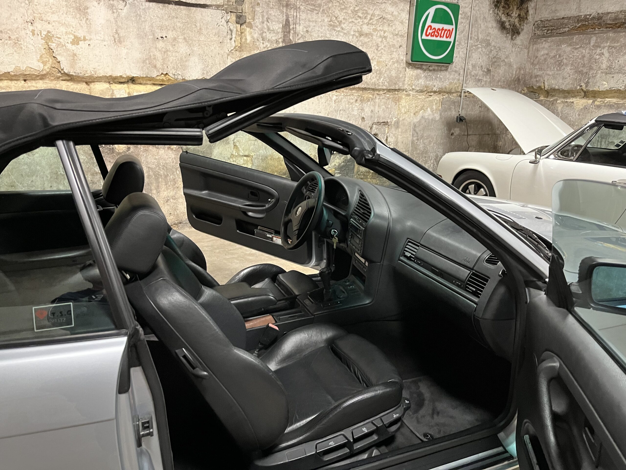 bmw cabrio vue depuis cote passager porte et capote ouverte avec en fond porsche targa capot ouvert